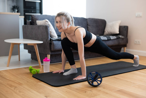Sportovní žena dělá cvičení na fitness podložku doma - Fotografie, Obrázek