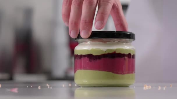 Pastry chef prepares layered creamy dessert in jar, parfait. Dessert preparation process. Video series - Footage, Video