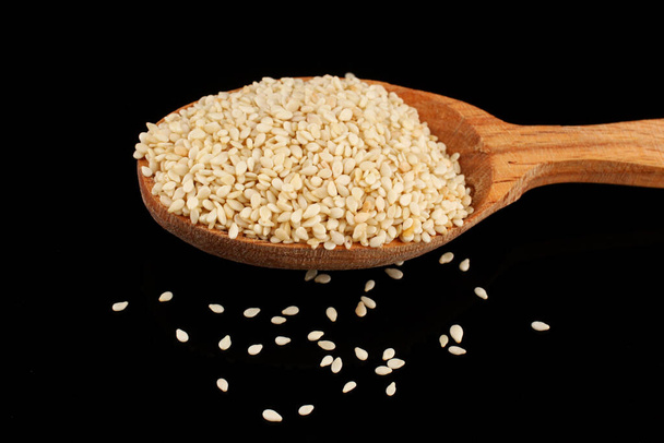 Sezamová semínka v lžíci na černém pozadí - Fotografie, Obrázek