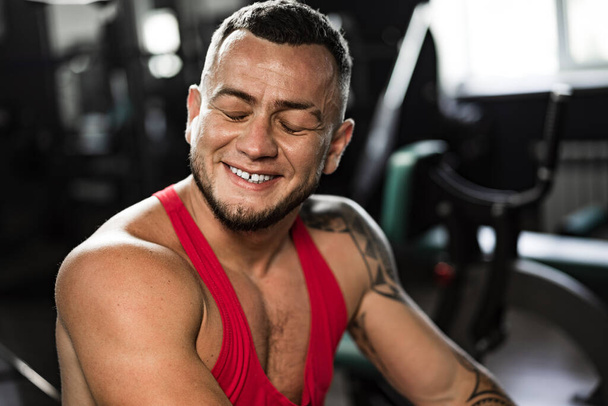 Portrait of man bodybuilder in red shirt in gym - Zdjęcie, obraz