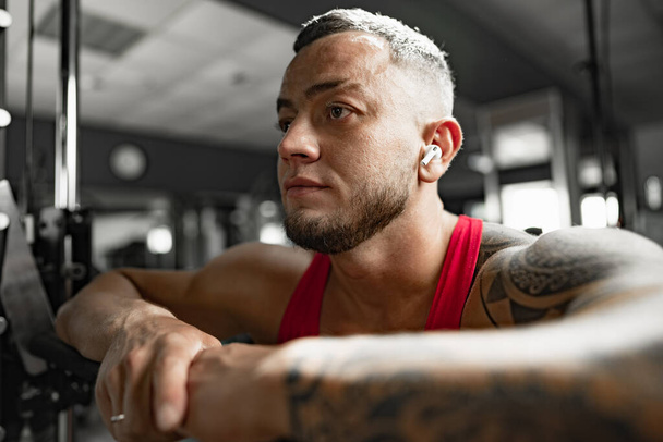 Portrait of man bodybuilder in red shirt in gym - Fotó, kép