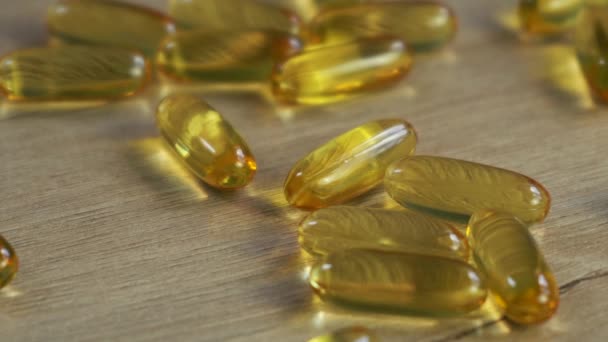 omega 3 capsule di olio di pesce si trovano su un tavolo di legno. - Filmati, video