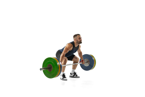 Full length portrait of a man in sportswear exercising with a weight isolated on white background - Photo, Image