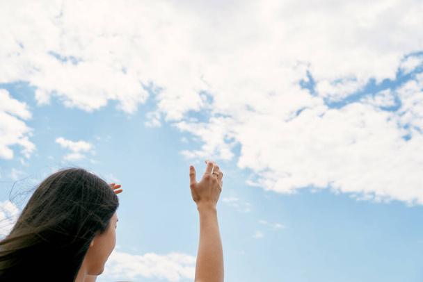 Το κορίτσι σηκώνει τα χέρια στον ουρανό. Προσεύχομαι στο Θεό. Κοντινό πλάνο - Φωτογραφία, εικόνα