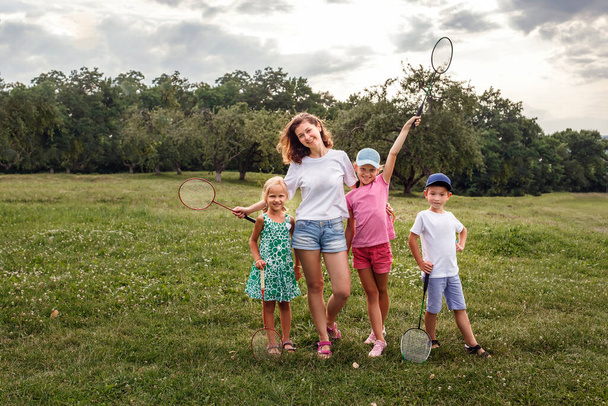 Mothers with children resting in nature. Young woman playing badminton with children - Foto, Imagem