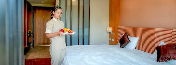 Hotel empregada segurando frutas tary no quarto de cama do hotel de luxo pronto para viagens turísticas. - Foto, Imagem