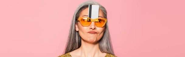 maturo asiatico donna in giallo occhiali da sole con carta di credito vicino fronte isolato su oink, banner - Foto, immagini