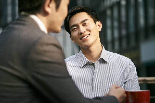 two asian corporate businesspeople discussing business at a outdoor coffee shop - Photo, Image