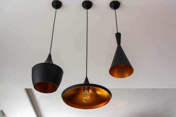 Three hanging lamps in black color in the style of an industrial loft in the interior. - Foto, afbeelding