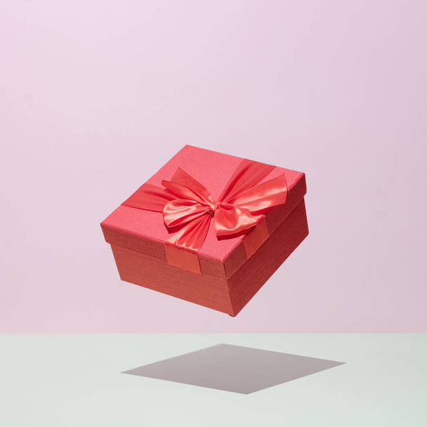 Geschenk in einer roten Schachtel in Schwebe auf einem pastellfarbenen Hintergrund Hochzeitsfeier Gratulationskonzept. - Foto, Bild