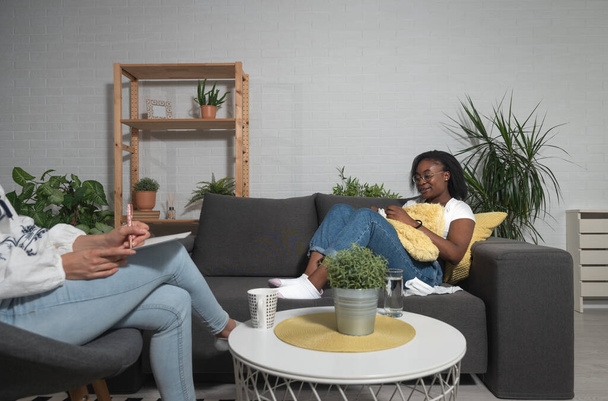 Young black woman sitting with a psychotherapist in the office has a conversation therapy session trying to solve the problem of depression and anxiety - Foto, afbeelding