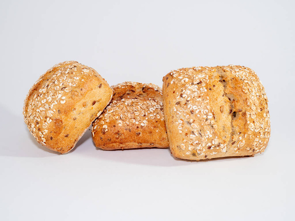 Ψητό ψωμάκι βουτηγμένο σε σπόρους σουσαμιού και πλιγούρι βρώμης απομονωμένο σε λευκό φόντο. . Υψηλής ποιότητας φωτογραφία.  - Φωτογραφία, εικόνα