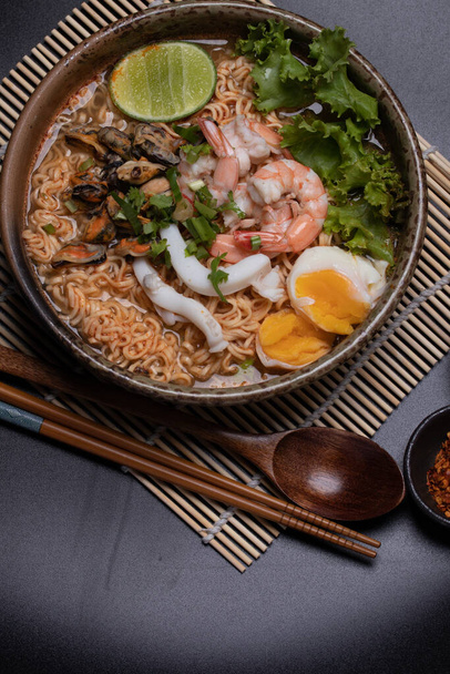 Лапша с морепродуктами, креветки, кальмары, мидии в коричневой керамической миске - Фото, изображение