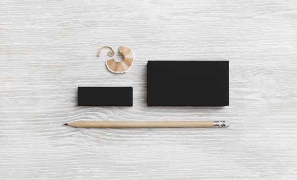 Blank black business card, pencil and eraser on light wooden background. Stationery mockup. Objects for placing your design. Top view. Flat lay. - Φωτογραφία, εικόνα