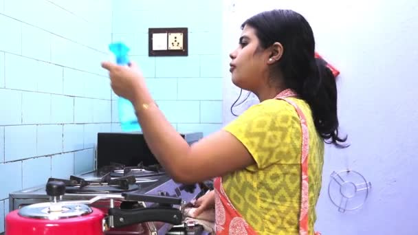 Önlük giyen güzel bir Hintli genç kadın mutfak temizleyicisiyle ev mutfağını temizliyor. - Video, Çekim
