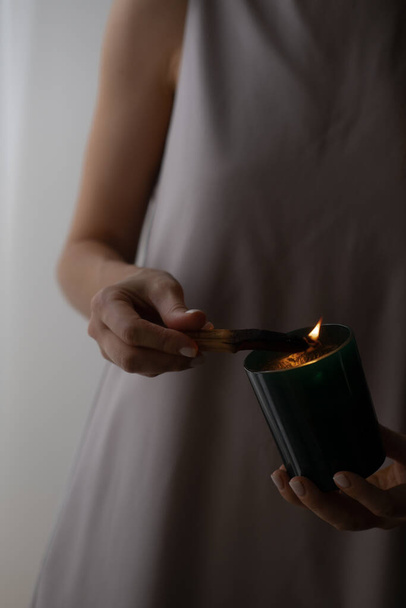 Γυναίκα κρατώντας στα χέρια palo santo ραβδί και κερί, κάψιμο καπνού, πνευματική πρακτική, ενέργεια καθαρισμού, επούλωση, διαλογισμό έννοια. Ατμοσφαιρική κυκλοθυμική φωτογραφία - Φωτογραφία, εικόνα