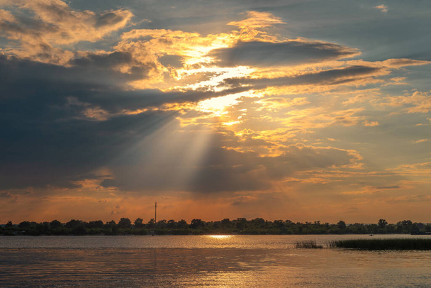 Sonnenuntergang am Fluss. Die Sonnenstrahlen bahnen sich ihren Weg durch die Wolken. Gutes Wetter. - Foto, Bild