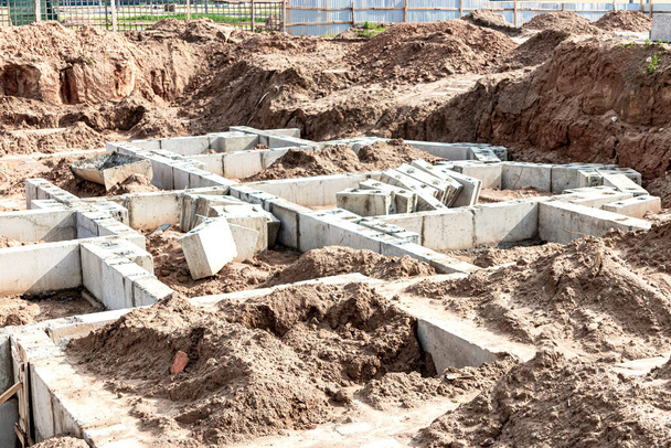 Beim Bau eines Hauses wird das Fundament aus großen Stahlbetonblöcken abgetrennt. Zuverlässiges Stahlbetonfundament. Baustelle - Foto, Bild