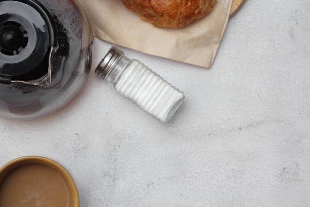Um croissant servido com café é colocado em uma mesa branca. - Foto, Imagem