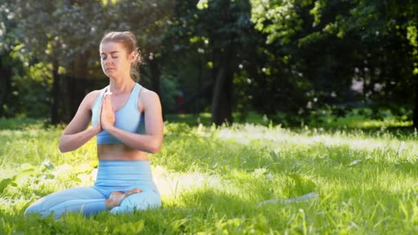 Nuori nainen meditoi joogassa aiheuttaa ja hengittää syvään - Materiaali, video