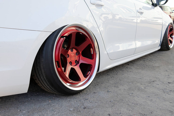 Tuned white car with extreme low suspension and red wheels. - Photo, Image
