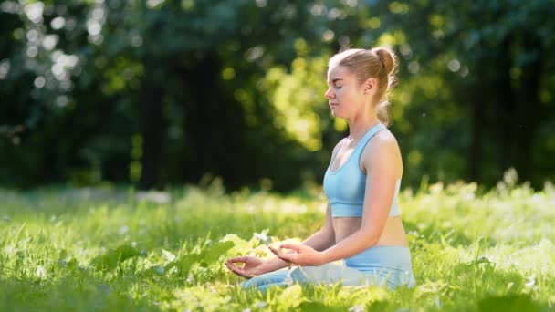 Blonde concentrée en survêtement pratique la méditation de yoga - Séquence, vidéo