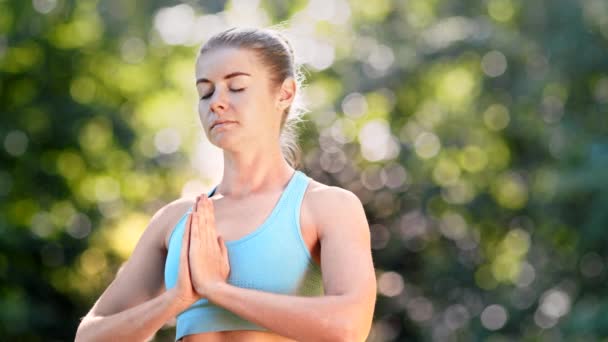 Femme concentrée pratiquant de yoga en haut bleu médite - Séquence, vidéo