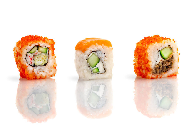 Set aus drei Sushi-Rollen auf weißem Hintergrund mit Spiegelung. Sushi-Rolle mit Reis, Tofu-Käse, fliegendem Fischrogen, Krabbenfleisch und Avocado, Lachs. Sushi-Menü. Japanische und asiatische Küche, Restaurant. - Foto, Bild