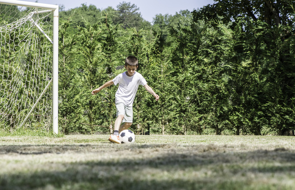 Child playing football in a stadium - Foto, imagen