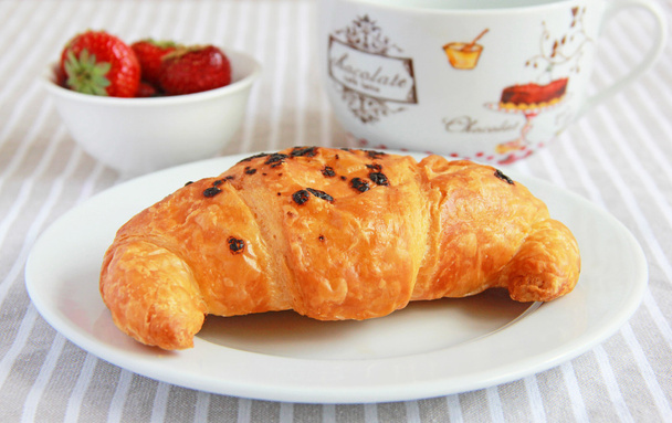 croissants met chocolade en aardbeien voor het ontbijt - Foto, afbeelding