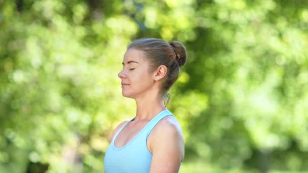 Lady with hair bun relaxes after exercises and meditates - Footage, Video