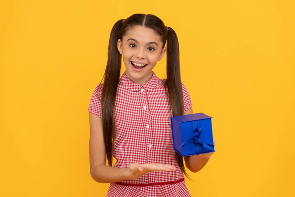 gelukkig kind presenteren geschenkdoos op gele achtergrond, vrouwen dag - Foto, afbeelding