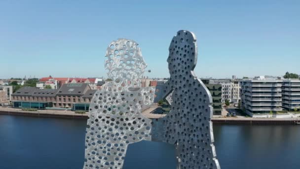 Orbita girata intorno alla parte superiore dell'opera d'arte Molecule Man in alluminio. Edifici sul lungomare del fiume Sprea sullo sfondo. Berlino, Germania - Filmati, video