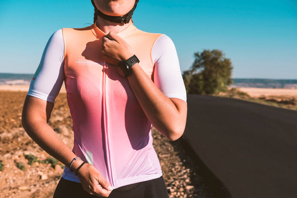 Primer plano de una joven ciclista sujetando su camiseta mientras sonríe. Concepto de ciclismo. Concepto deportivo. - Foto, imagen