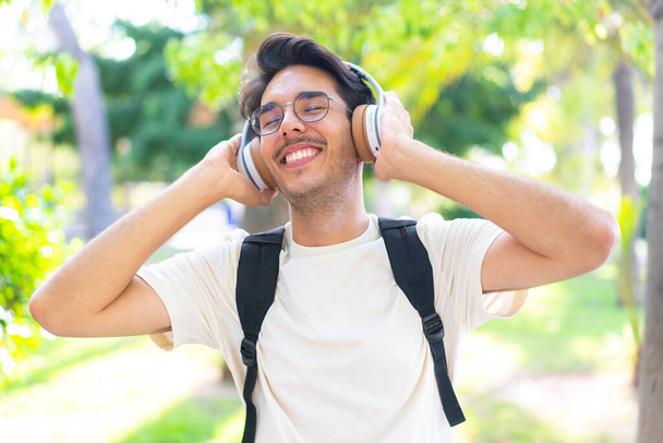 Joven estudiante al aire libre escuchando música - Foto, Imagen