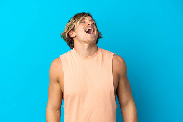 Schöner blonder Mann isoliert auf blauem Hintergrund lachend - Foto, Bild