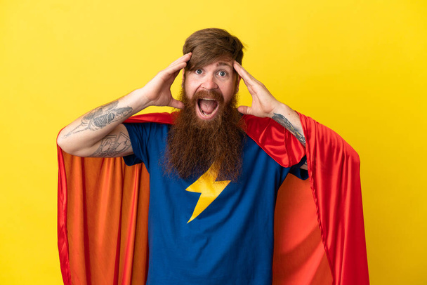 Roodharige Super Hero man geïsoleerd op gele achtergrond met verrassingsexpressie - Foto, afbeelding