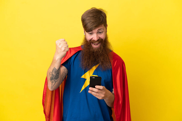 Redhead Super Hero man isolated on yellow background surprised and sending a message - Photo, Image
