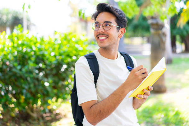 Joven estudiante al aire libre sosteniendo un cuaderno - Foto, imagen
