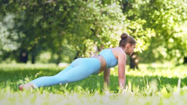 Young woman athlete practices static yoga pose on meadow - Footage, Video