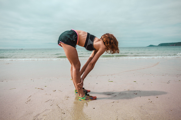 jonge vrouw stretching op het strand - Foto, afbeelding