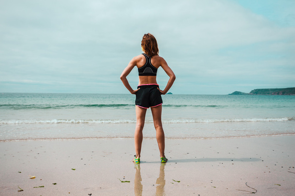 Fit young woman standing on the beach - Foto, Imagen