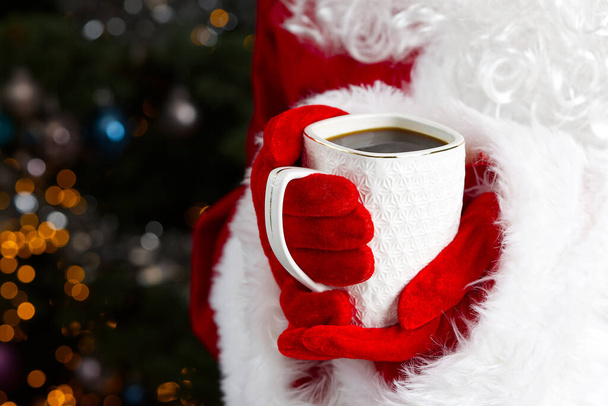 Weihnachtsmann mit weißem Becher mit Kaffee in der Hand, Nahaufnahme. - Foto, Bild
