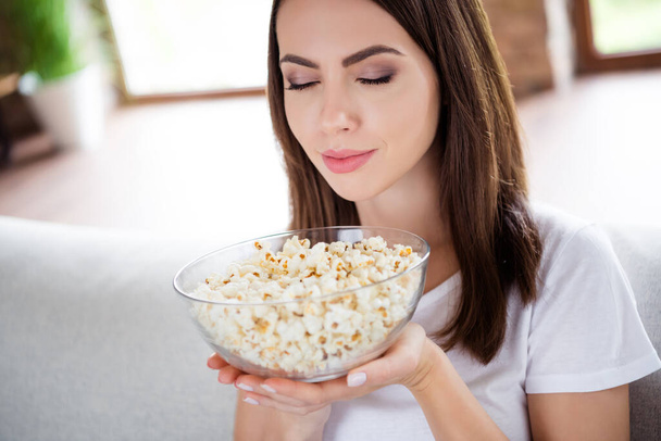Photo of calm happy young charming woman hold bowl popcorn smell food indoors inside house home flat - Fotografie, Obrázek