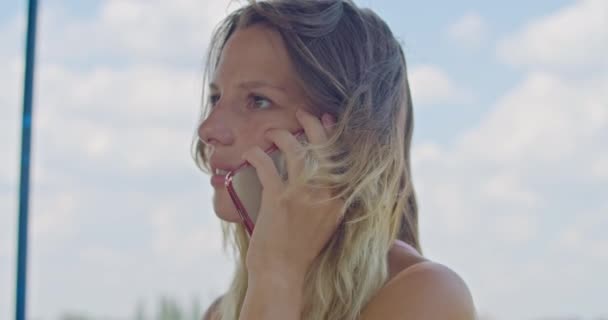 the blonde girl speaks on the phone, smiles, learned the good news. - Materiał filmowy, wideo