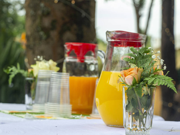 A decorative table with glass jugs of juice - Zdjęcie, obraz
