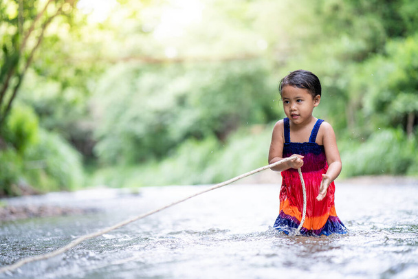 An asian cute female child playing with a string in a river - Foto, Imagen