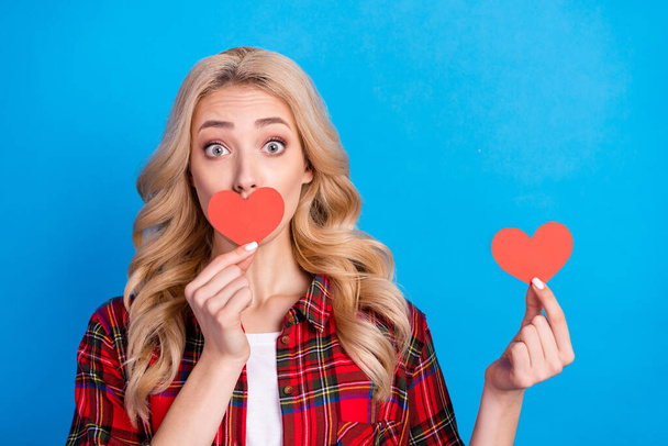 Photo of sweet impressed young woman dressed checkered shirt red heart cover lips big eyes isolated blue color background - Foto, Imagen