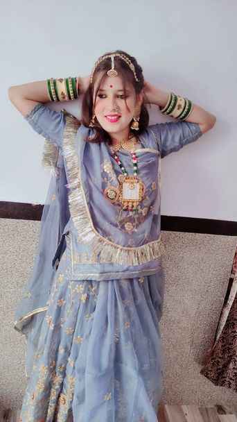 Μια όμορφη νεαρή Ινδή που φοράει ένα παραδοσιακό φόρεμα σάρι και ποζάρει. - Φωτογραφία, εικόνα