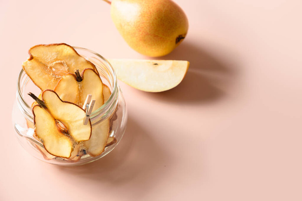 Pear chips in glass jar on pink background with copy space. - Valokuva, kuva